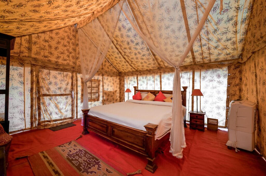 Elegant interior of a luxury tent in Jaisalmer, with wooden bed and cozy decor.